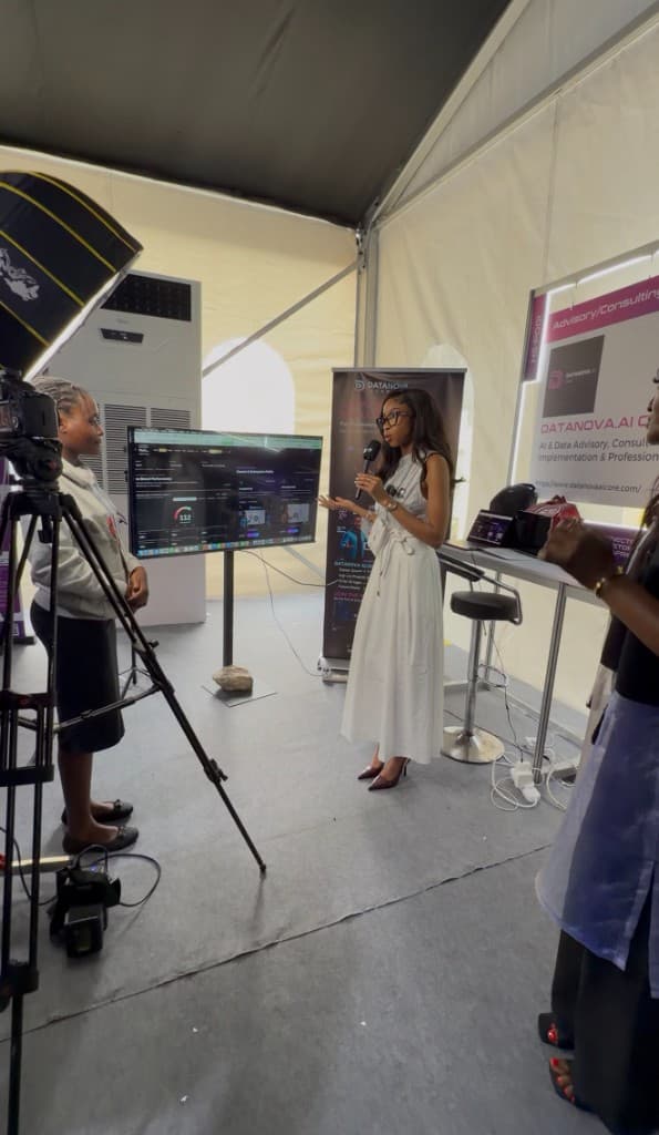 A DataNova colleague speaking on camera beside the stand screen.